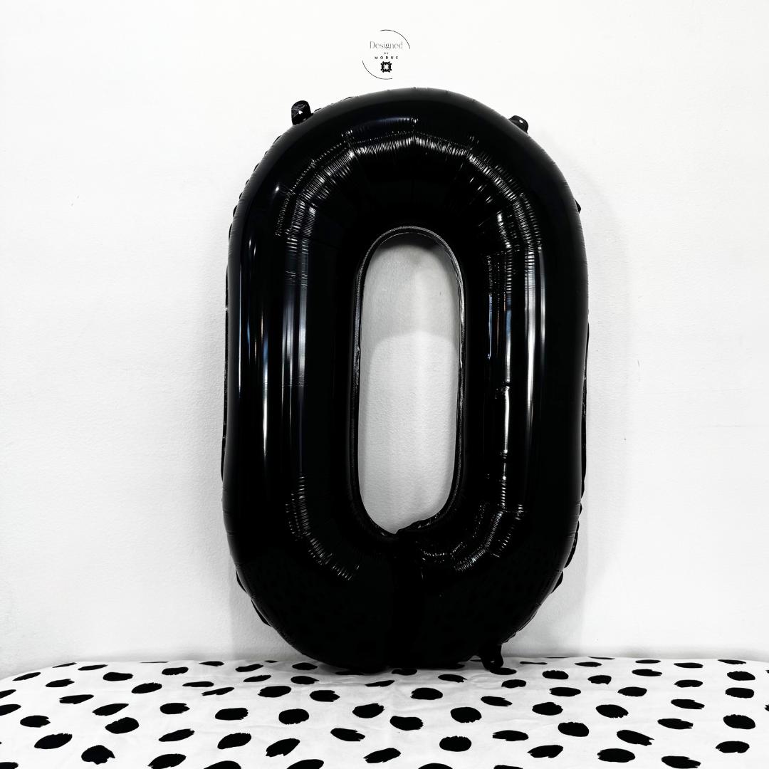 Black number 0 foil balloons together on white wall with dotted surface.