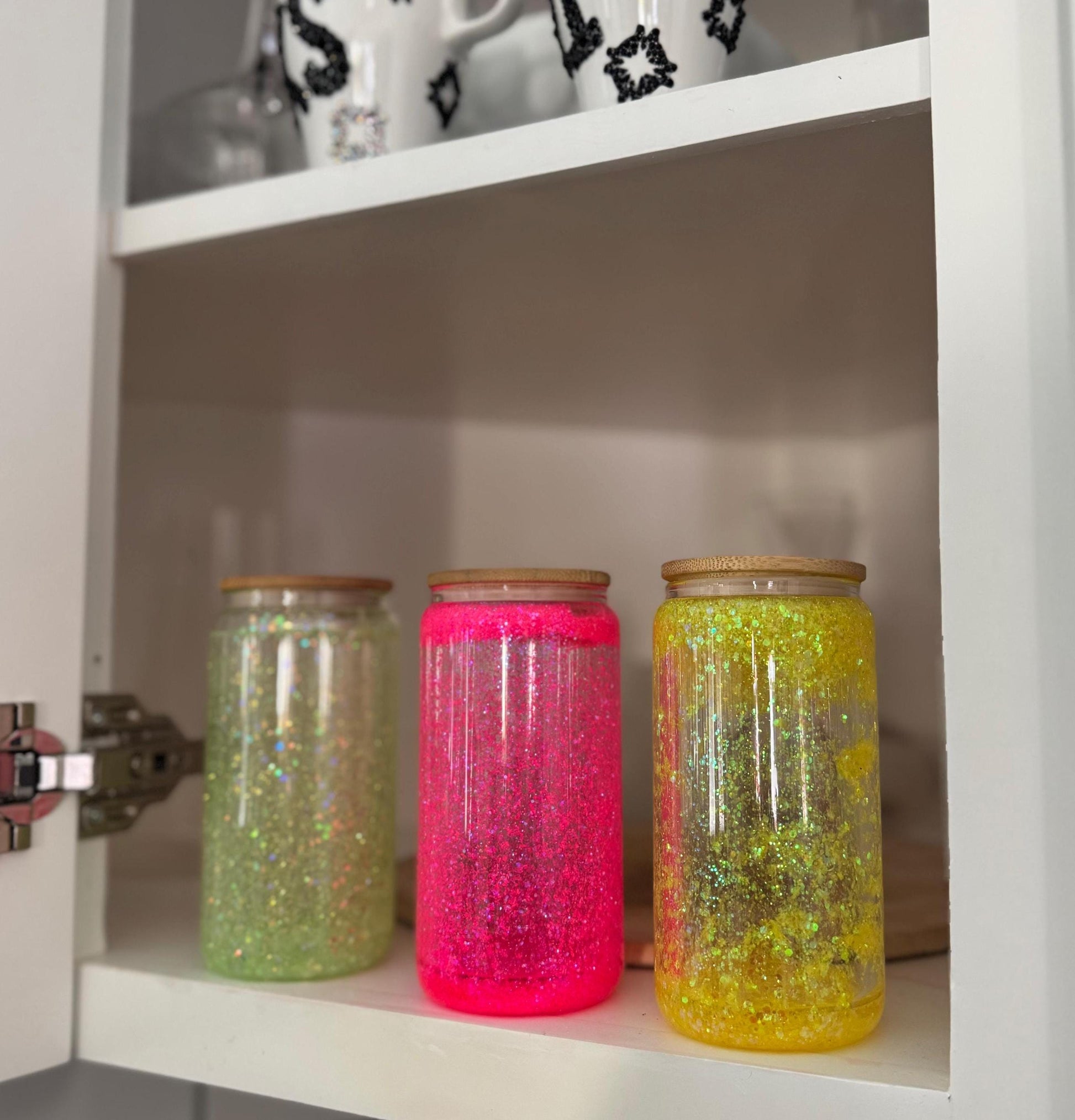 three Neon Glass Tumblers for Iced Coffee displayed in a white kitchen cabinet