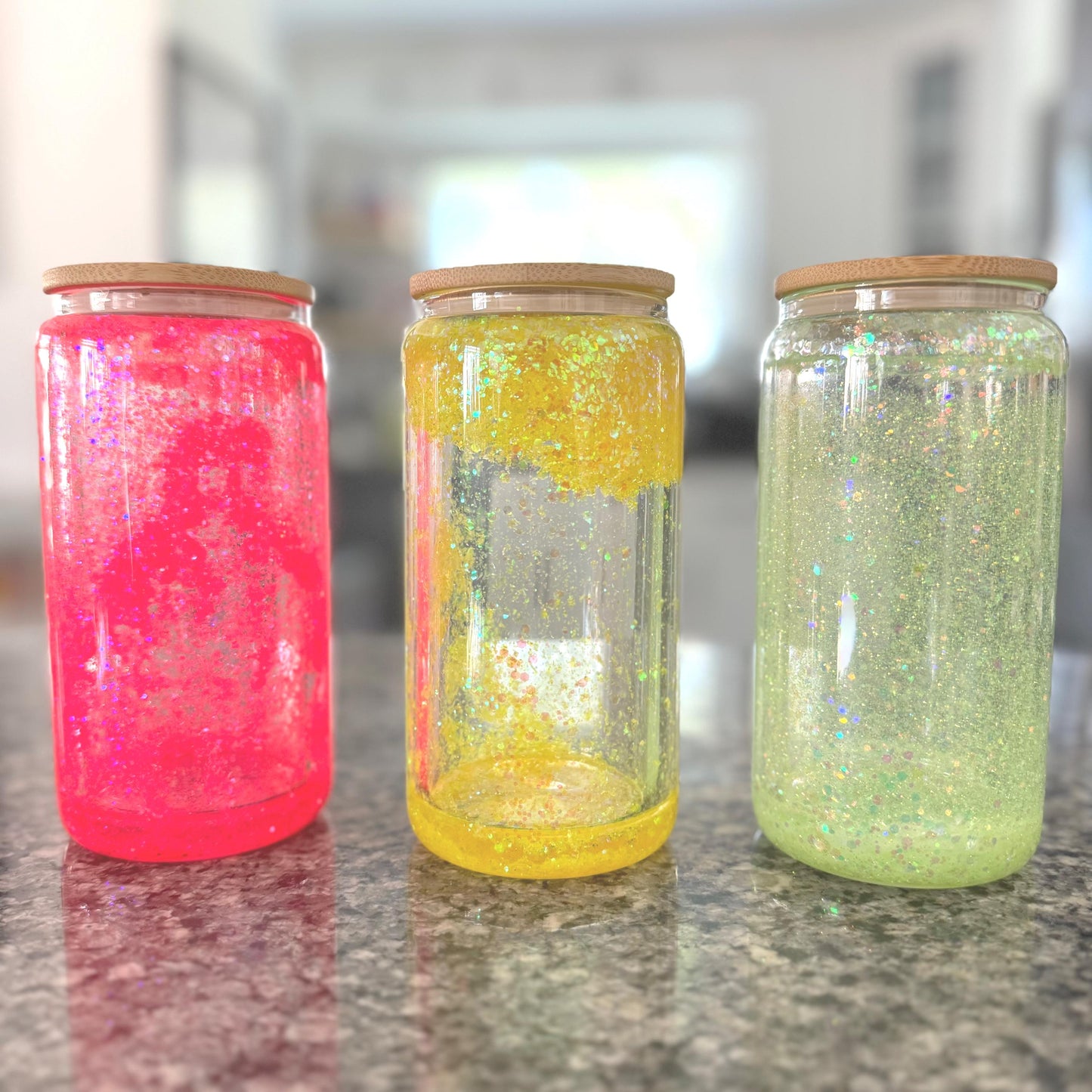 Pink, Yellow, Green, Neon  Glitter Snow Globe Glass Tumblers with bamboo lids on a kitchen counter