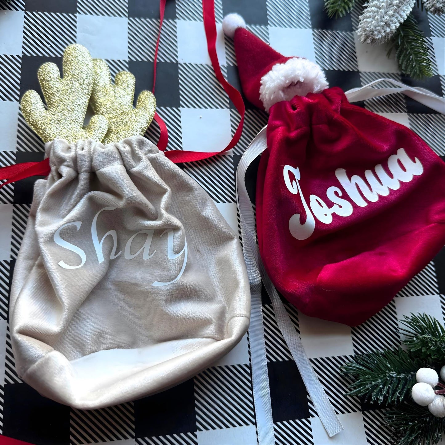 Matching personalized Christmas gift bags — red Santa hat and golden reindeer velvet pouches with names for festive gifting.