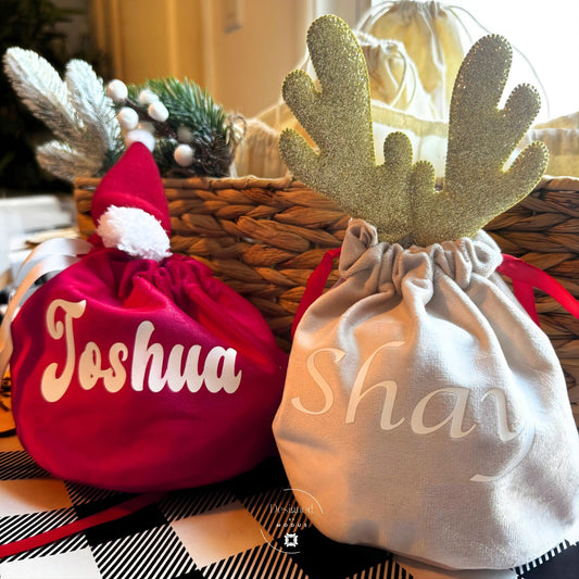 Personalized Christmas gift bags — red Santa hat and golden reindeer design with custom names, festive velvet holiday decor.