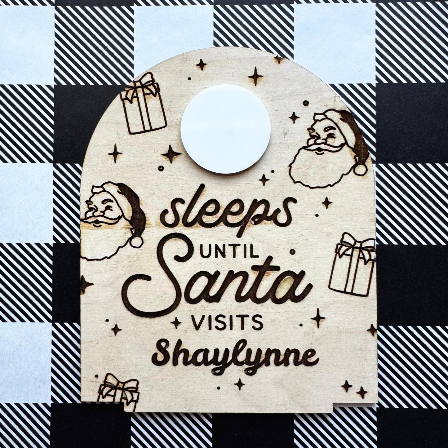 Custom engraved “Sleeps Until Santa” countdown board displayed on tabletop with woven basket and neutral Christmas decor background.