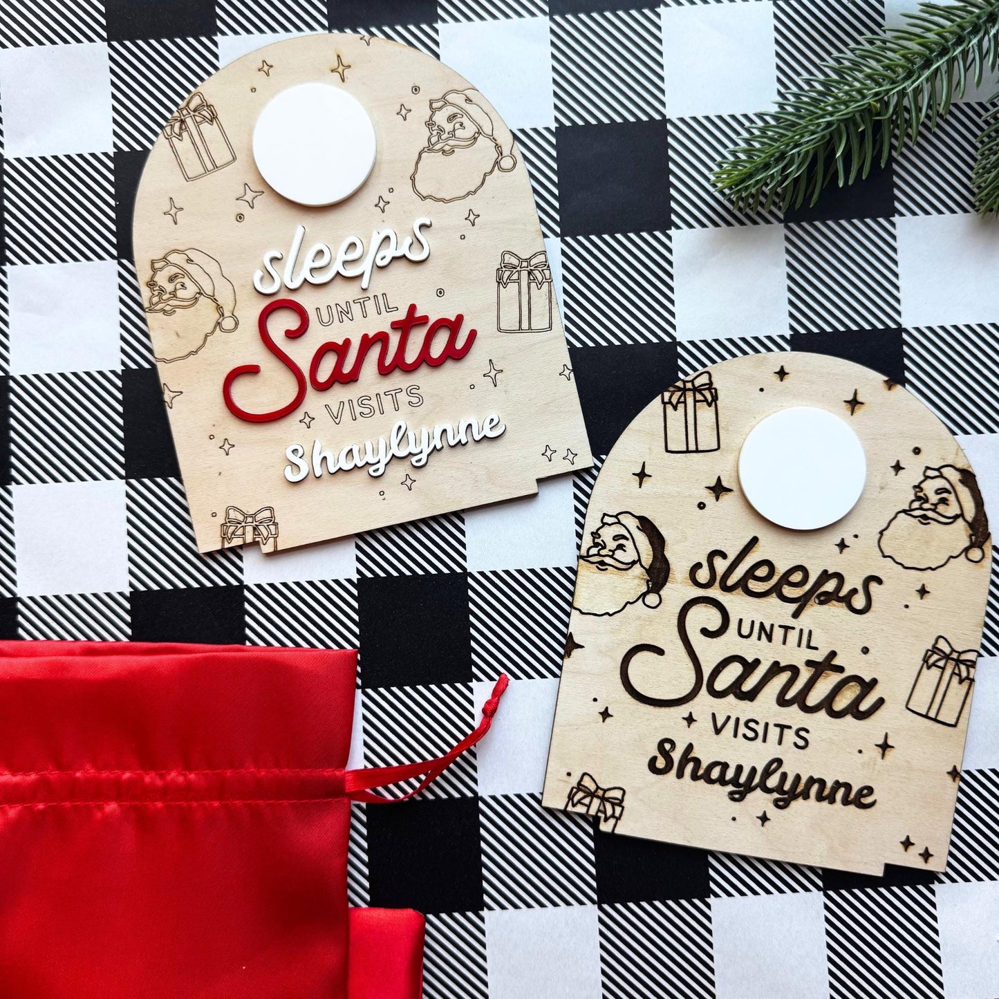 wo personalized Christmas countdown signs side by side, one engraved and one with 3D red lettering, displayed on festive checkered background with red gift bag.