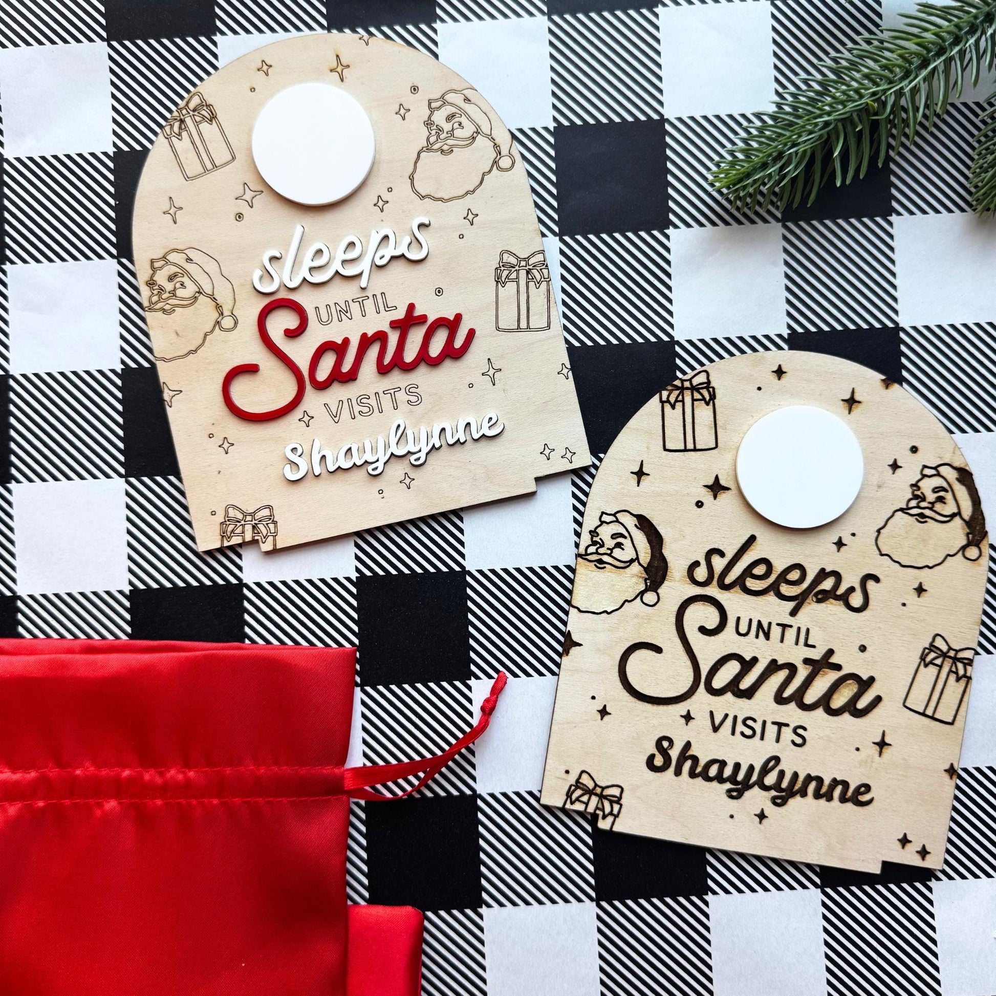 wo personalized Christmas countdown signs side by side, one engraved and one with 3D red lettering, displayed on festive checkered background with red gift bag.