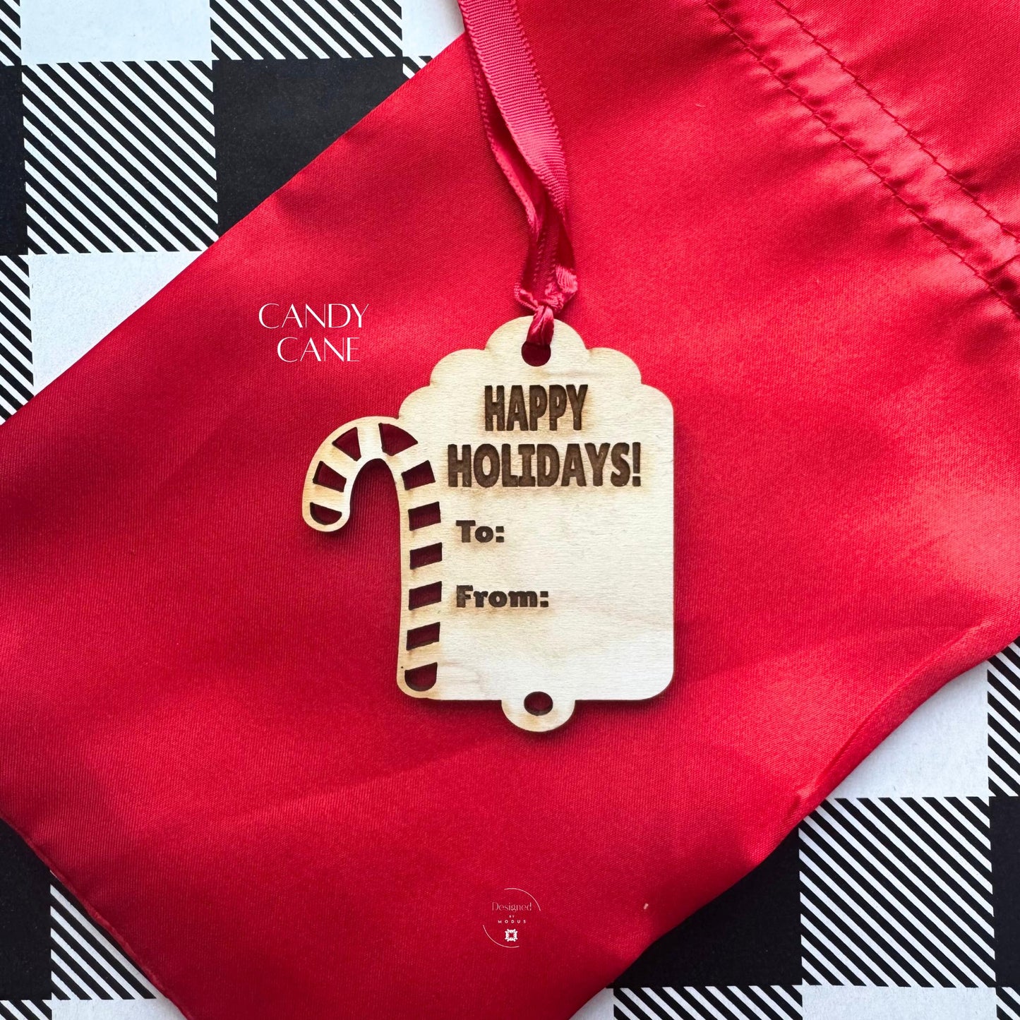 Candy Cane wooden holiday tag with engraved “Happy Holidays,” tied with red ribbon on a festive background.