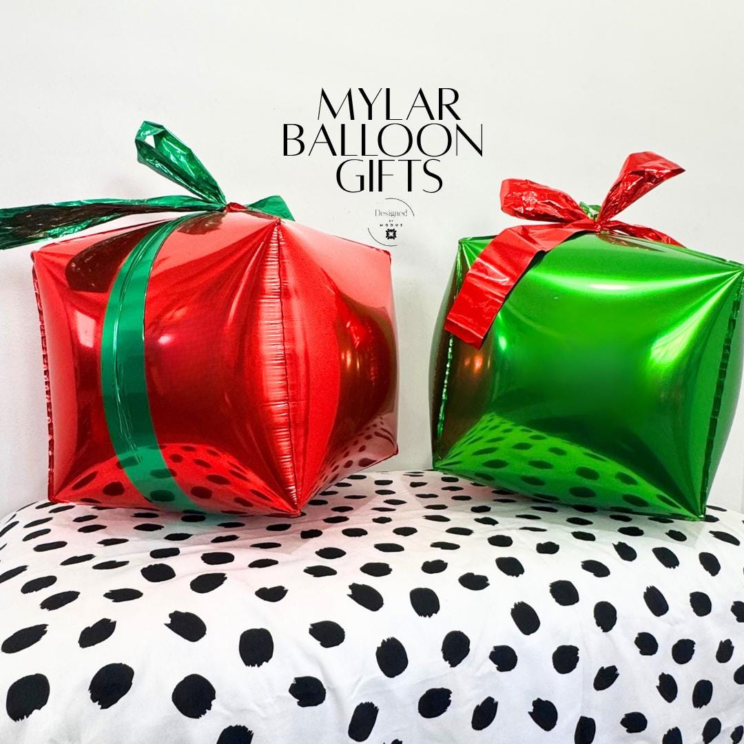Red and green mylar gift-shaped balloons with metallic bows used as Christmas party decor props.”