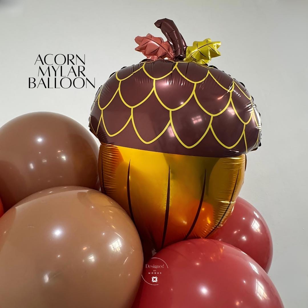 Acorn mylar balloon in brown and gold tones surrounded by fall-colored latex balloons for autumn decor.”