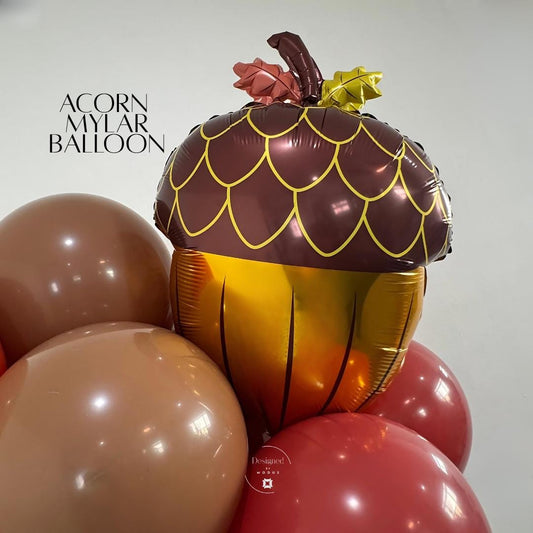 Acorn mylar balloon in brown and gold tones surrounded by fall-colored latex balloons for autumn decor.”