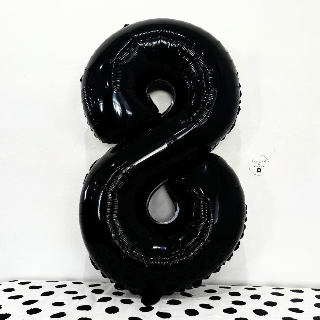 Black number 8 foil balloon with glossy finish on minimalist dotted background.