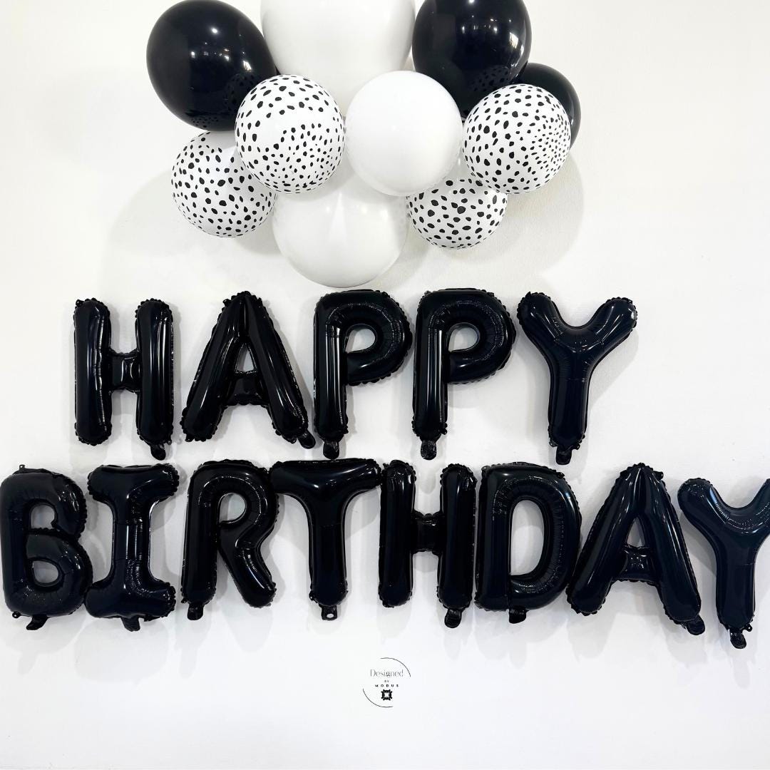 Entire “HAPPY BIRTHDAY” foil banner displayed beneath black-and-white balloon cluster.
