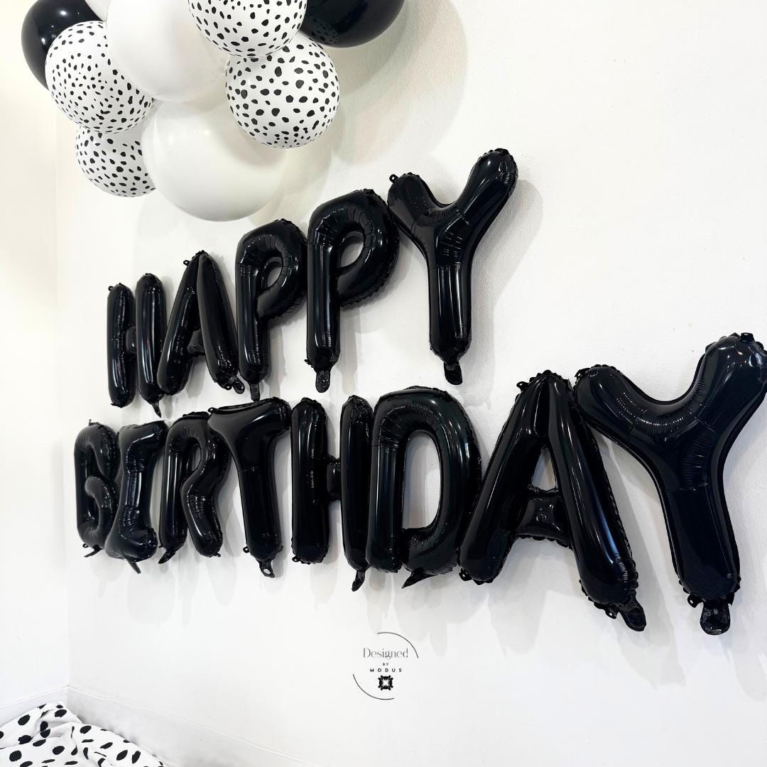 Side angle of black foil “Happy Birthday” balloons with patterned balloon arch accent.