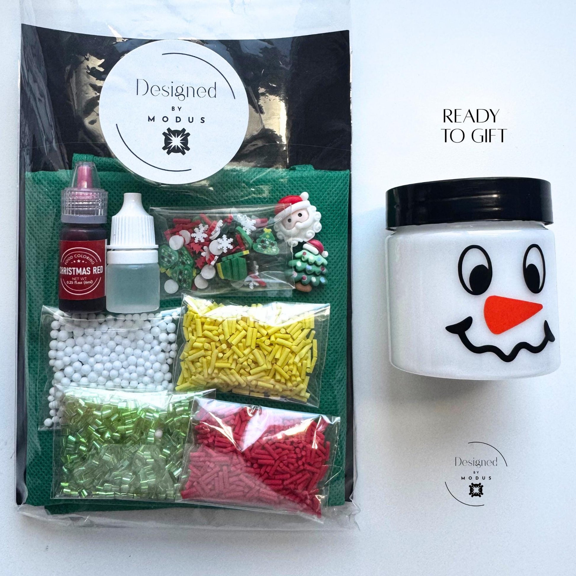Christmas slime kit packaged with pre-made white slime in a snowman jar, holiday mix-ins, dye, activator, and Designed by Modus label, captioned “Ready to Gift.&quot;