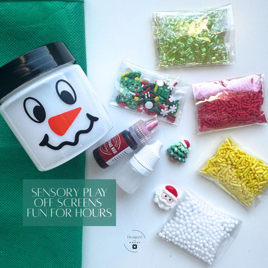 Flat lay of Christmas slime kit contents including snowman jar, activator, red dye, holiday charms, and sprinkles with the text “Sensory Play Off Screens Fun for Hours.”