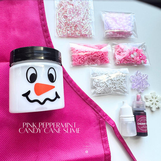 Pink Peppermint Candy Cane Slime Kit with white slime in snowman jar, pink apron, dye, activator, and assorted pink, white, and iridescent mix-ins displayed flat lay.