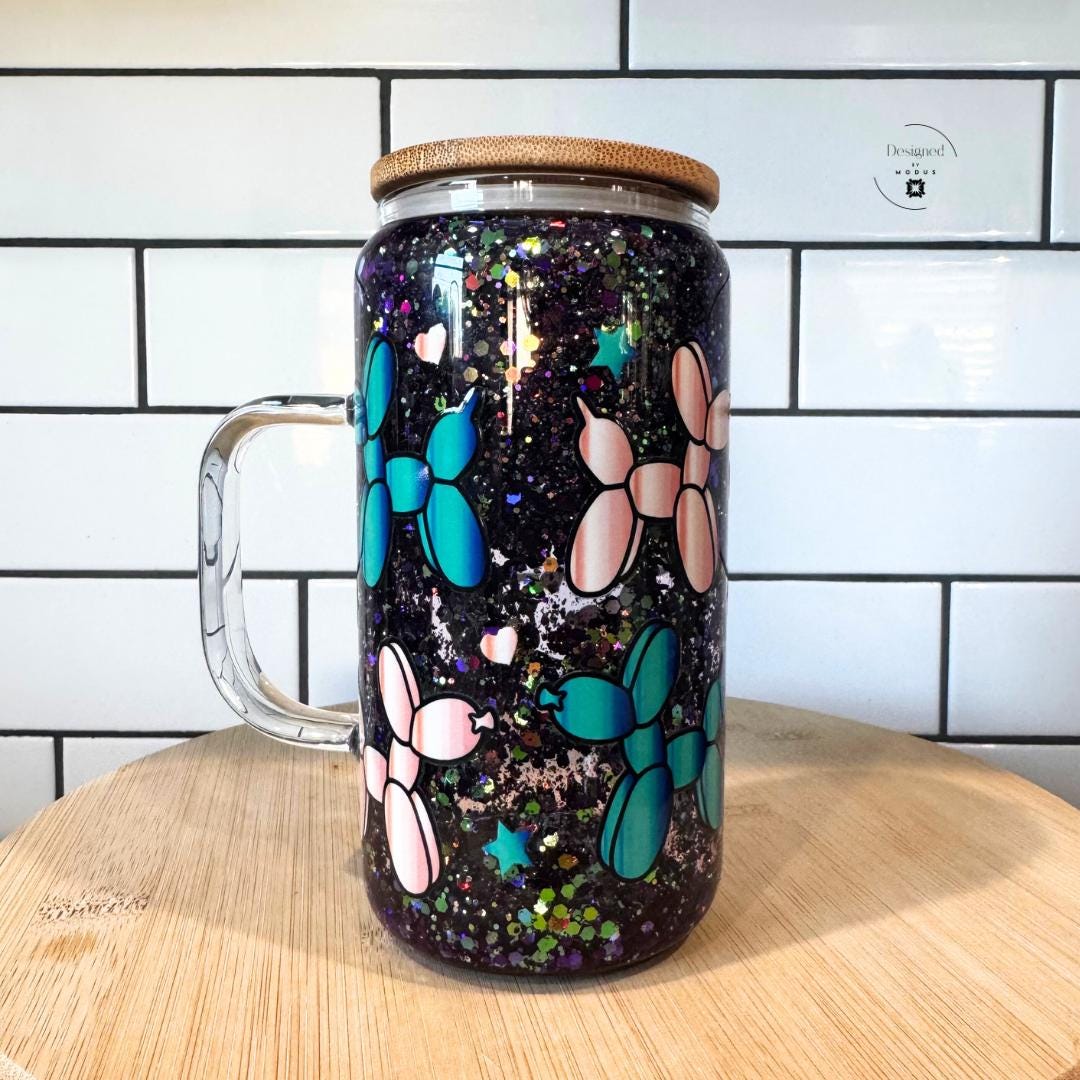 Balloon-dog glitter mug with bamboo lid and black-and-white bow on glass straws.