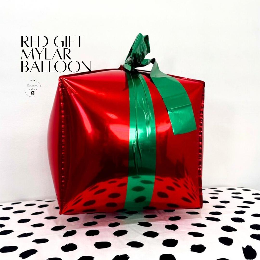 “Red and green mylar gift-shaped balloons with metallic bows used as Christmas party decor props.”