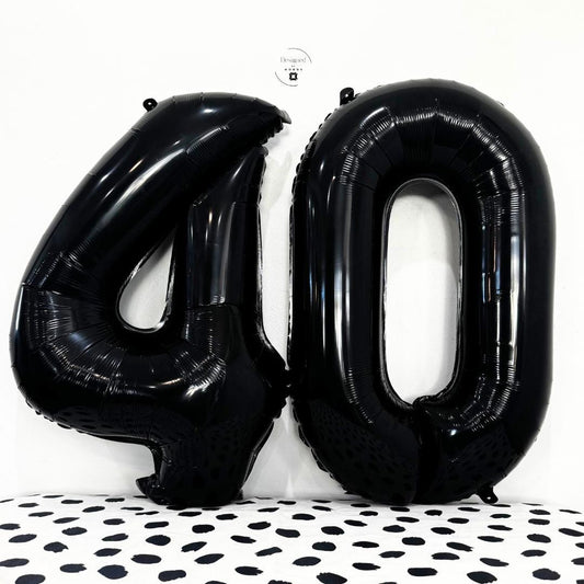 Black number 4 and number 0 foil balloons together on white wall with dotted surface.