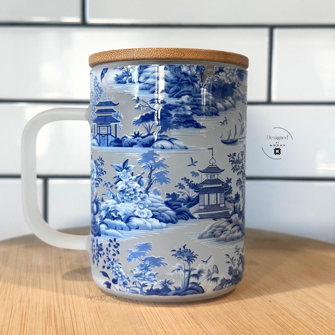 Front-facing view of blue and white snowglobe glass cup with handle.