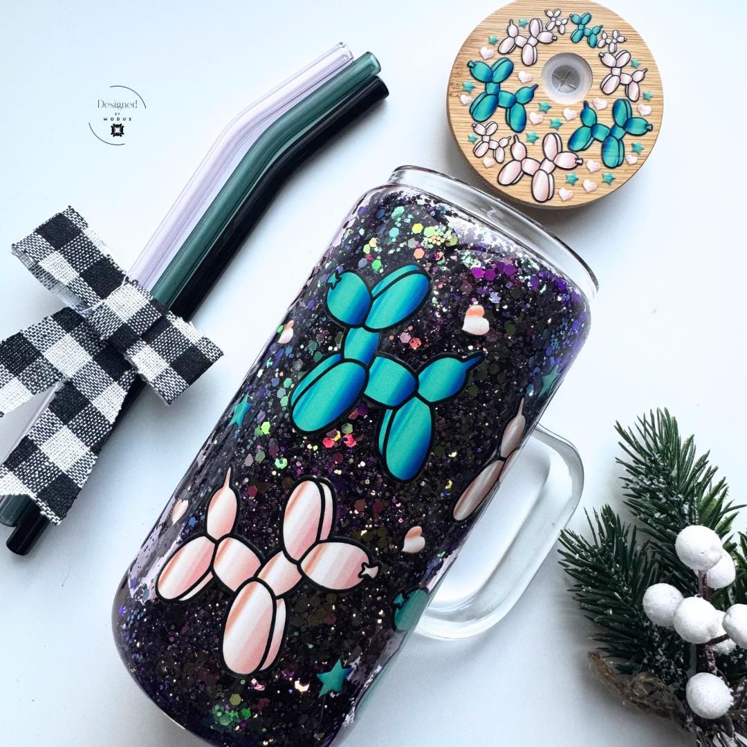 Glitter glass mug with pink and teal balloon-dog design, bamboo lid, and three glass straws