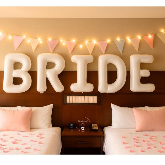 White BRIDE balloons above bed with lights and rose petals