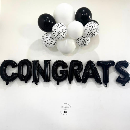 “Black Congrats letter balloons with black and white mini balloon cluster on white wall – party backdrop”