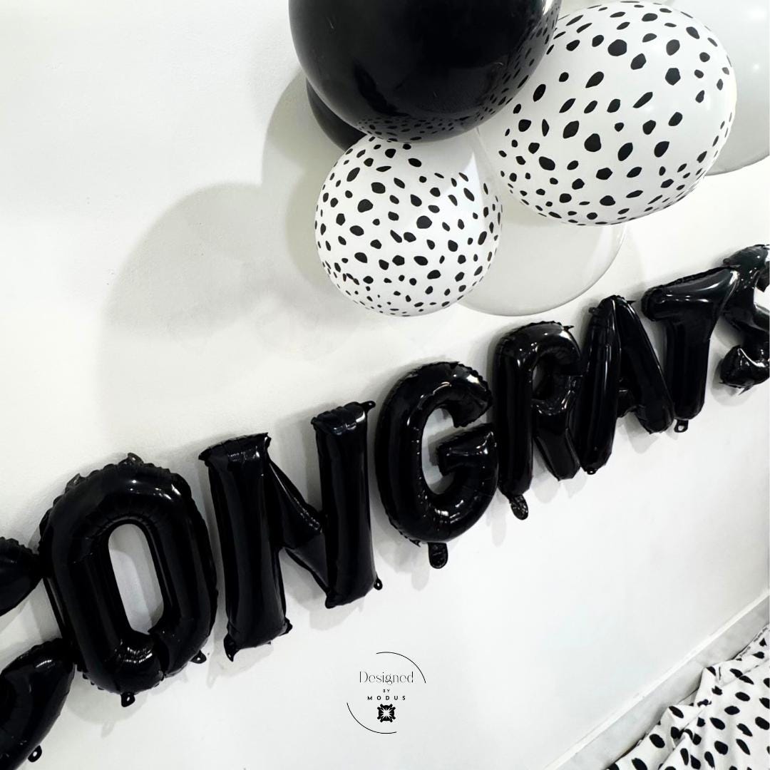 Side angle of Congrats balloon banner with monochrome balloon bundle above