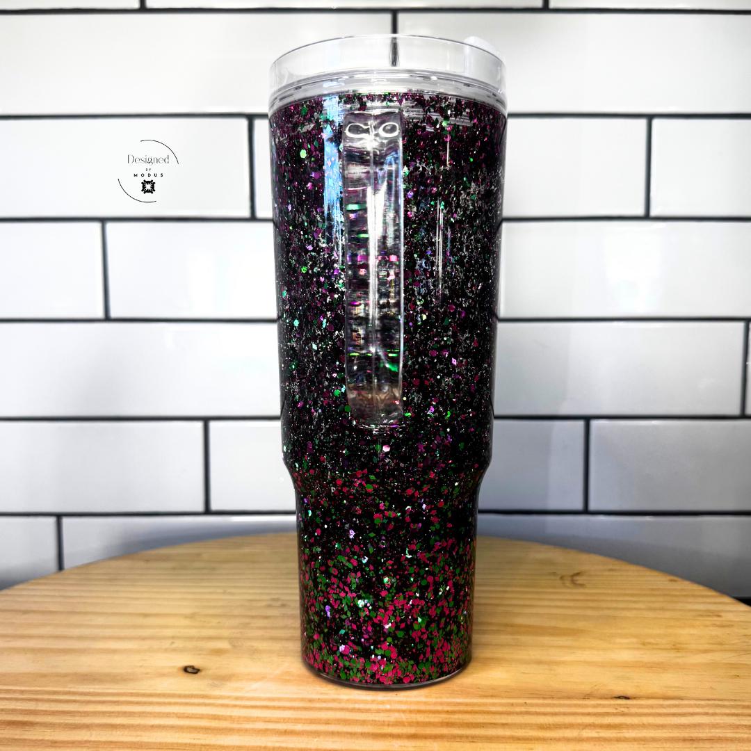 Black snow globe tumbler with hot pink and green holographic glitter and clear handle on wood surface-Travel Mug Design Glitter Snow Globe Tumbler Daily Hydration Companion Iced Coffee Container Water Bottle Alternative Hot Pink Green Holographic Sparkle Aesthetic Floating Glitter Movement Clear Handle Feature Slide Lid Protection 40oz