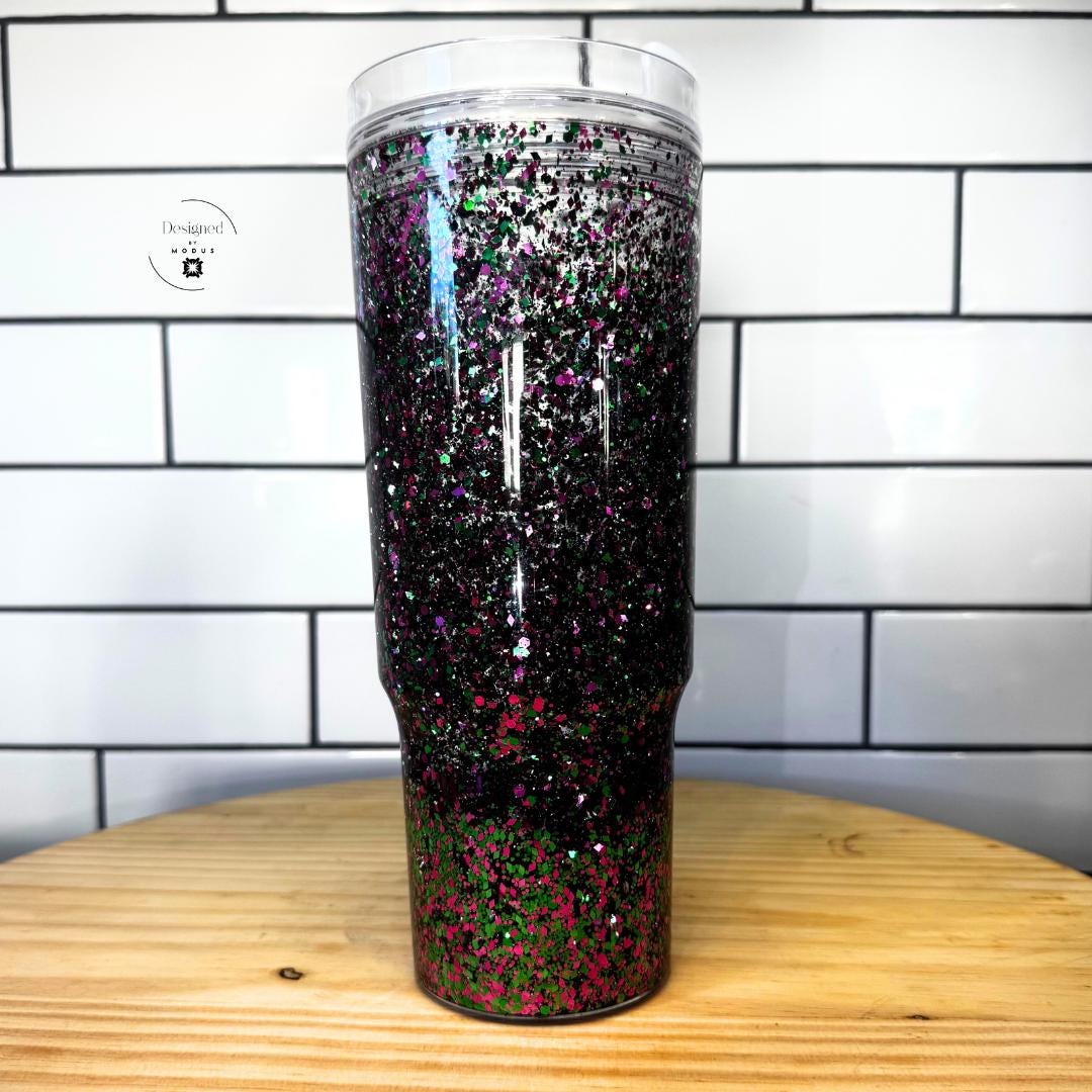 Tall black glitter tumbler showing pink and green sparkle effect in double wall-Aesthetic Drinkware Collection Glitter Snow Globe Tumbler Holographic Cup Design Statement Piece Accessory Hot Pink Green Color Scheme Floating Sparkle Effect Eye Catching Appearance Clear Handle Feature Slide Lid Convenience 40oz Capacity