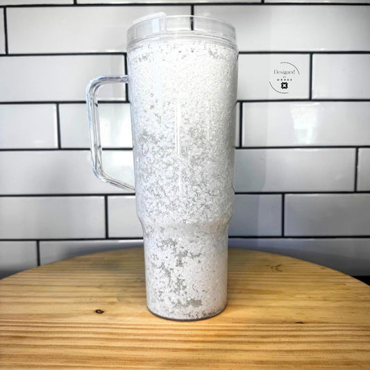 White iridescent glitter snow globe tumbler with clear handle on wooden table
