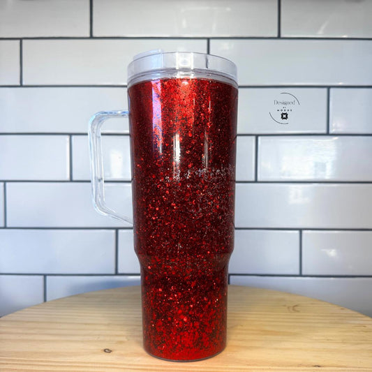 1️⃣ Red glitter snow globe tumbler standing on wooden table with bright sparkle effect