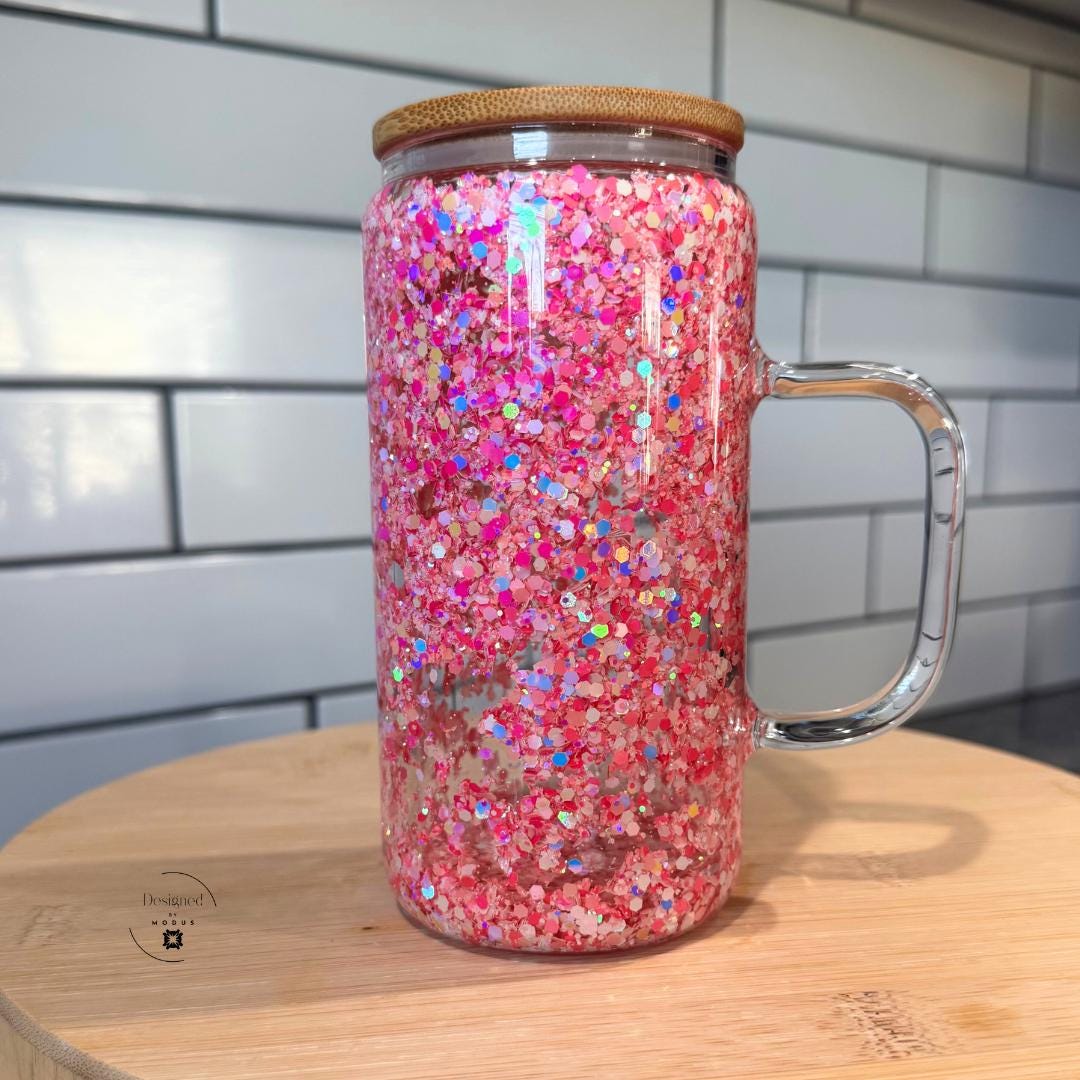 Pink glitter glass tumbler with handle on wooden stand