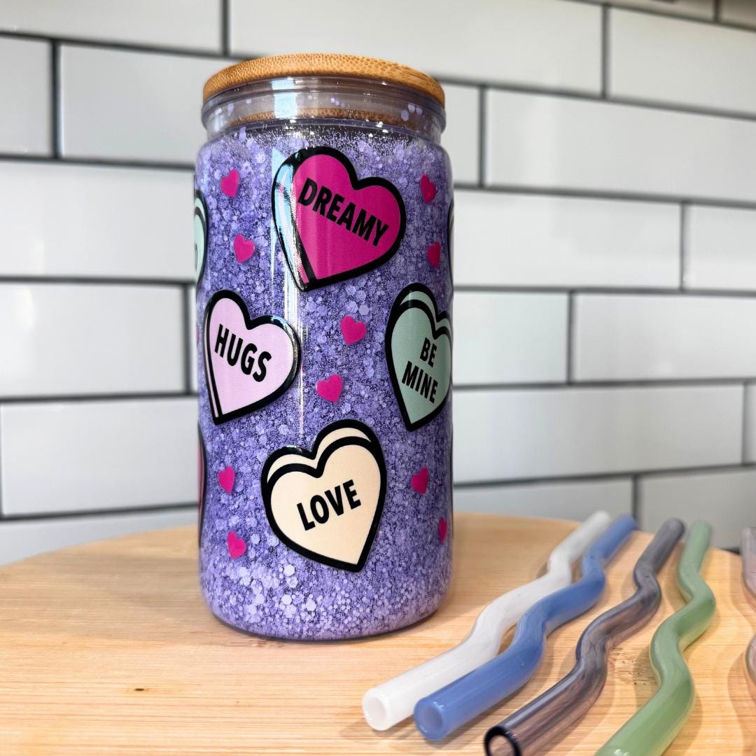 Purple snowglobe tumbler showing Be Mine and Love heart stickers with wavy straws next to cup
