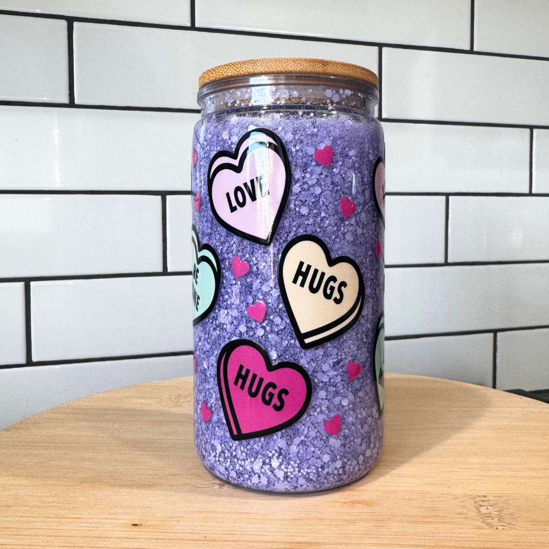 Purple Valentine snow globe tumbler with conversation hearts and bamboo lid on wood table