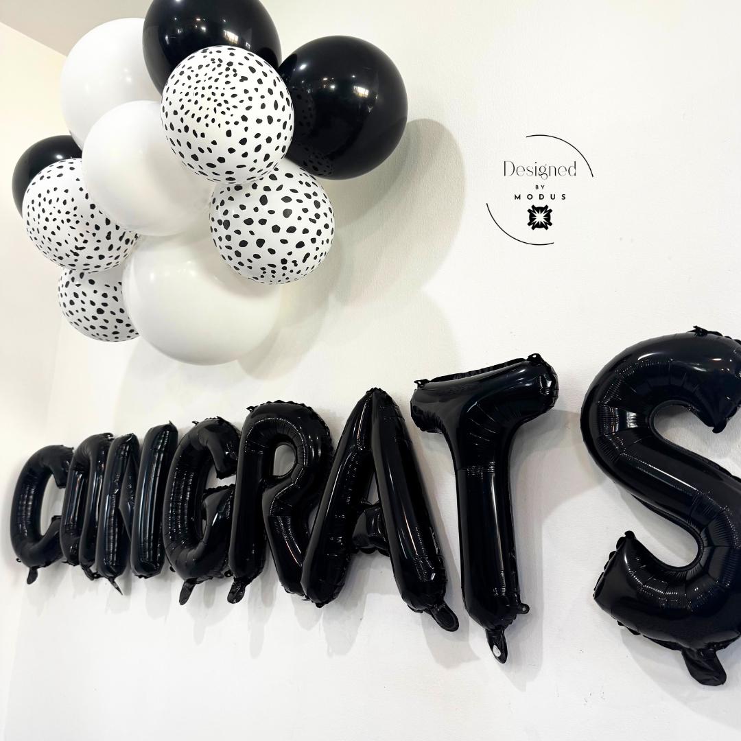 “Close-up of black foil Congrats balloons and dalmatian print balloons – modern party decor”