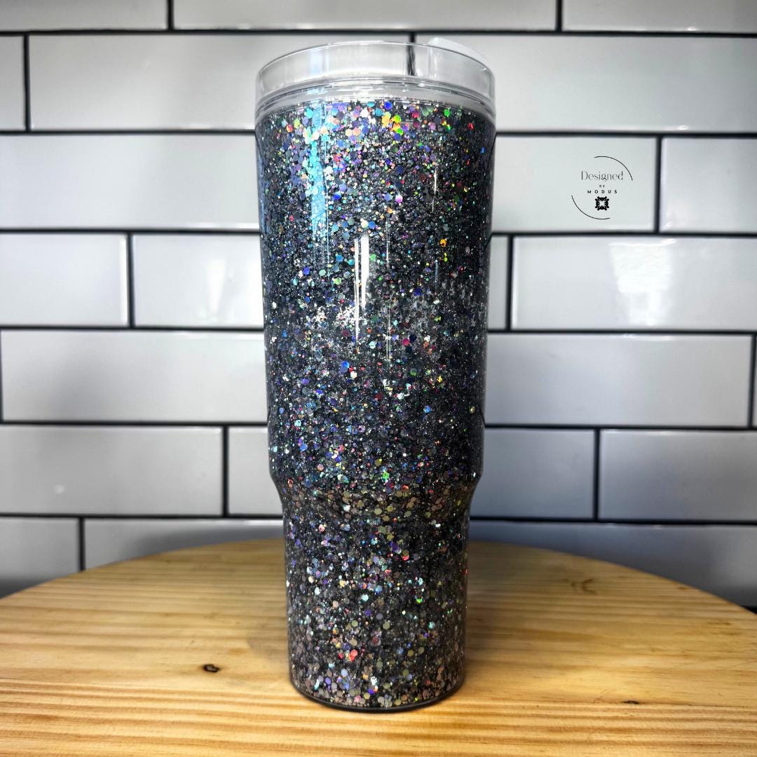 Tall chrome glitter snow globe cup displayed on wood surface