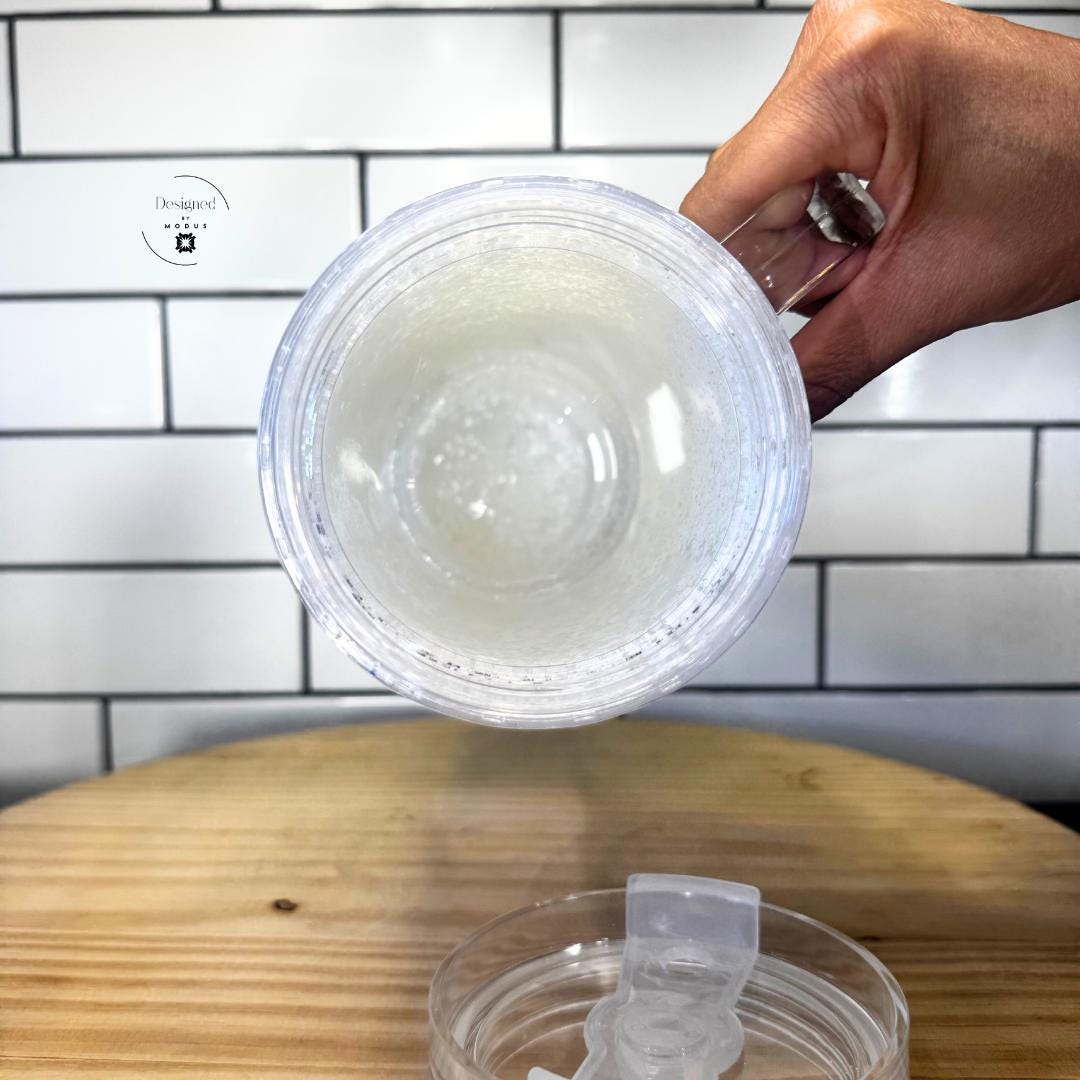Clear slide lid placed beside white iridescent glitter handle tumbler
