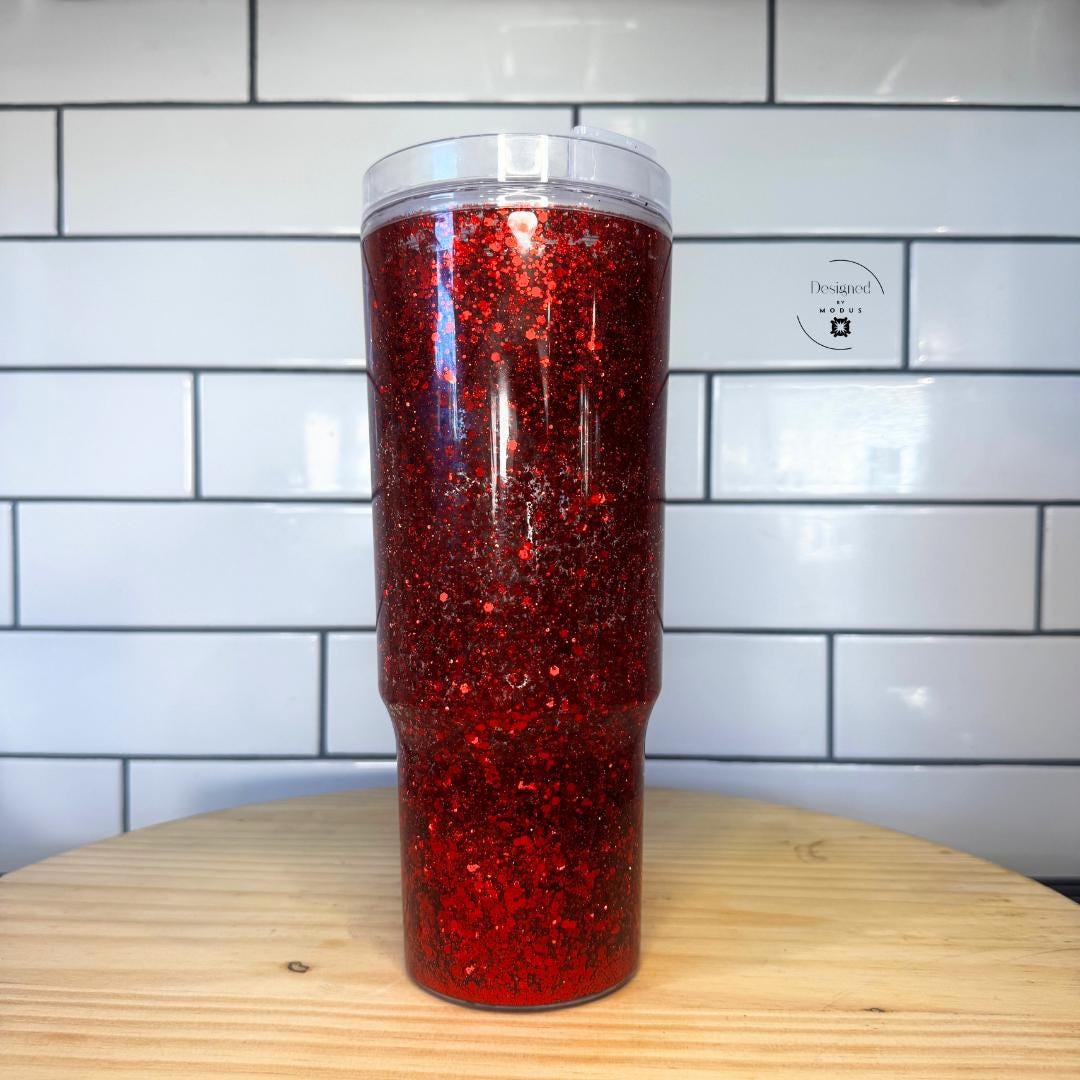 Side view of red glitter handle tumbler against white tile background