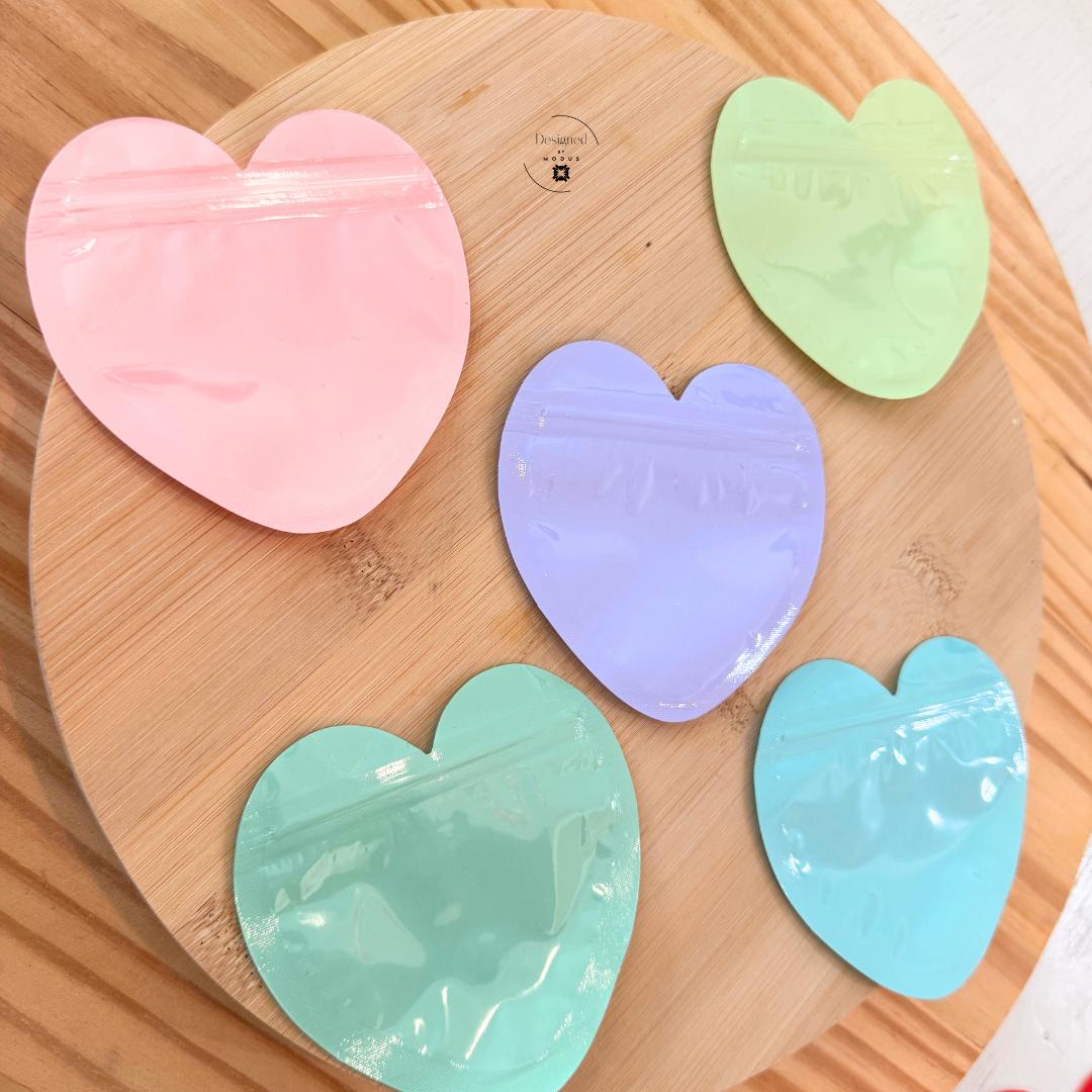 Heart shaped resealable bags in pastel colors stacked on wood background