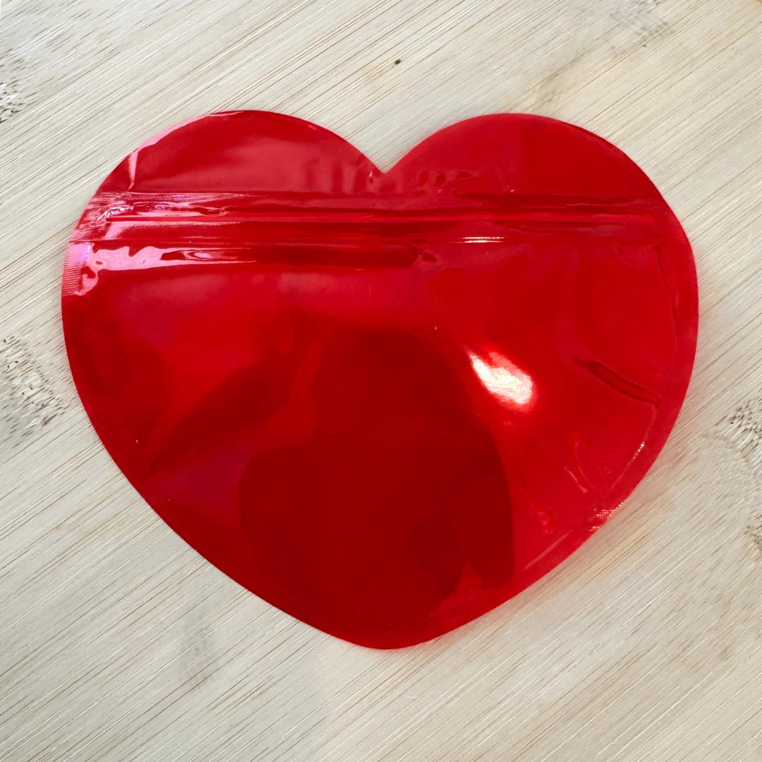 Red heart shaped resealable bag empty on wooden surface