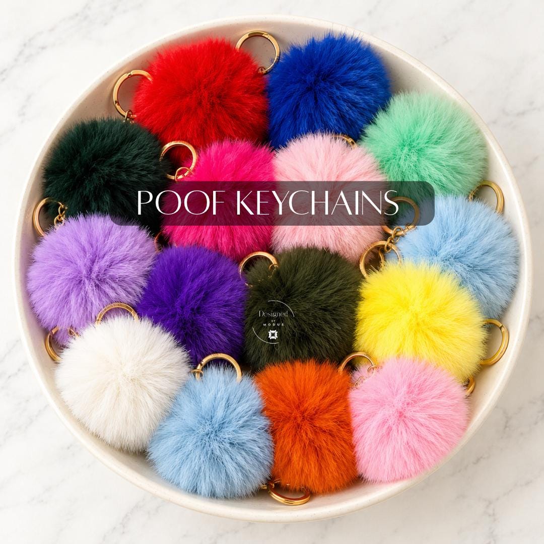 Colorful fluffy pom pom keychains displayed together in a white bowl, featuring assorted bright, pastel and neutral shades with gold-tone metal key rings. Soft faux fur-style bag charms for purses, handbags, backpacks, tote bags and keys. Cute Christmas stocking stuffers, small gifts for women and teens, teacher appreciation presents, birthday party favors and everyday fashion accessories.