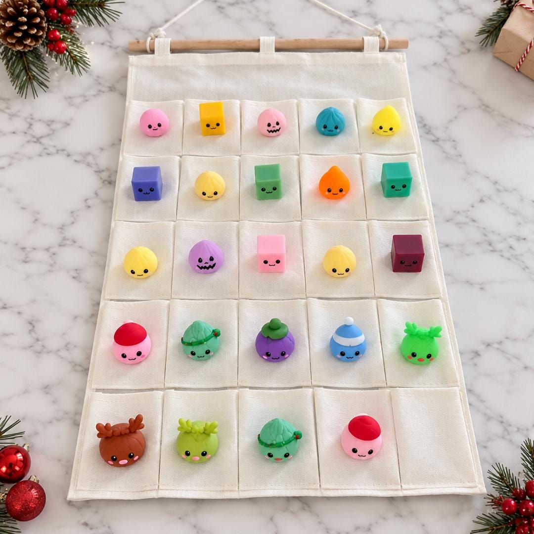 Personalized Christmas countdown calendar featuring cream fabric, 25 numbered pockets with alternating pink and red lettering, custom child's name and festive Christmas Countdown heading. Includes 24 colorful miniature squishy toys for daily surprises from December 1 through December 24. Reusable Christmas advent calendar for kids ages 5 and up, pink Christmas decorations, holiday sensory toy gifts and personalized family Christmas traditions.